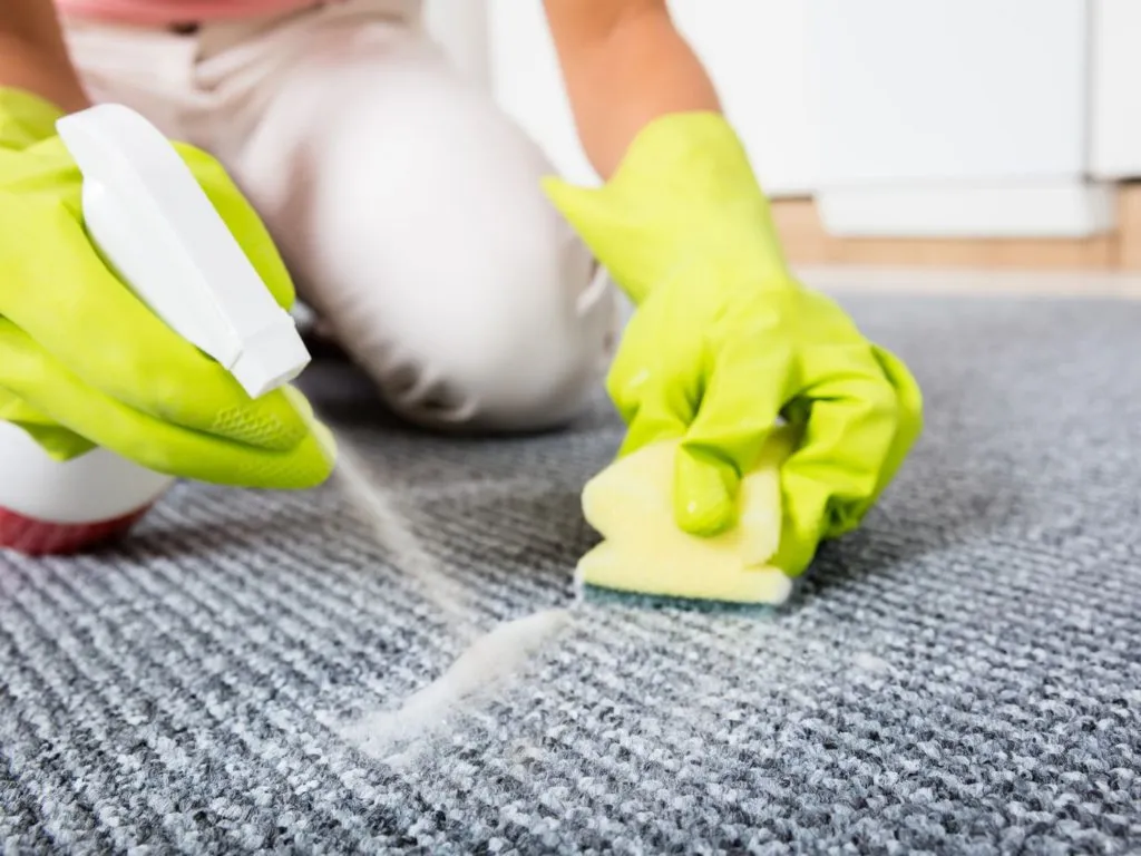 a person is cleaning smokers soot from carpet