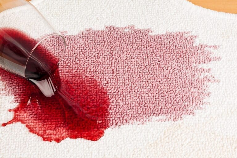 close shot of a wine glass and wine stain spilled on carpet